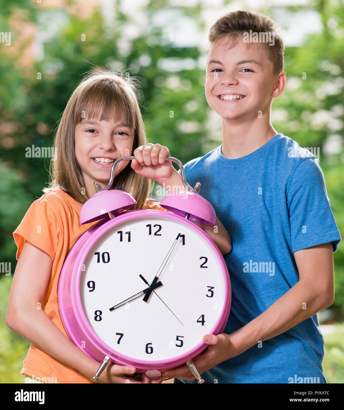 Un ragazzo e una ragazza con grande orologio Foto Stock