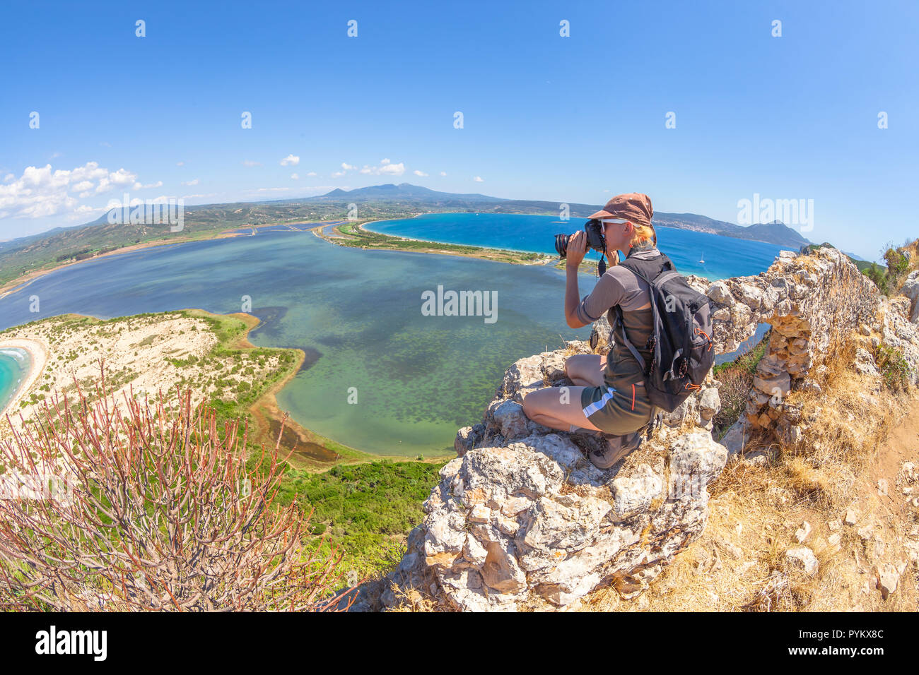 Femmina di viaggio prende colpi di scenic Voidokilia Beach dal castello di Navarino rovina in Pylos, Peloponneso e Grecia dopo escursioni.escursionista donna fotografa un greco popolari punti di riferimento. Fish Eye Foto Stock