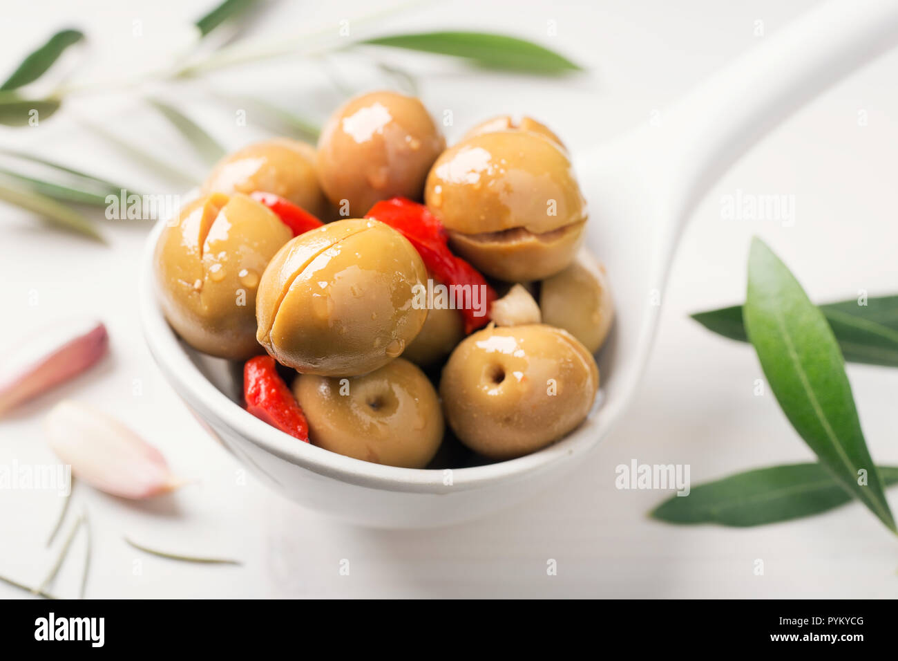 Dividere le olive sul cucchiaio bianco e bianco sullo sfondo di legno. Lo spagnolo tapa. Foto Stock