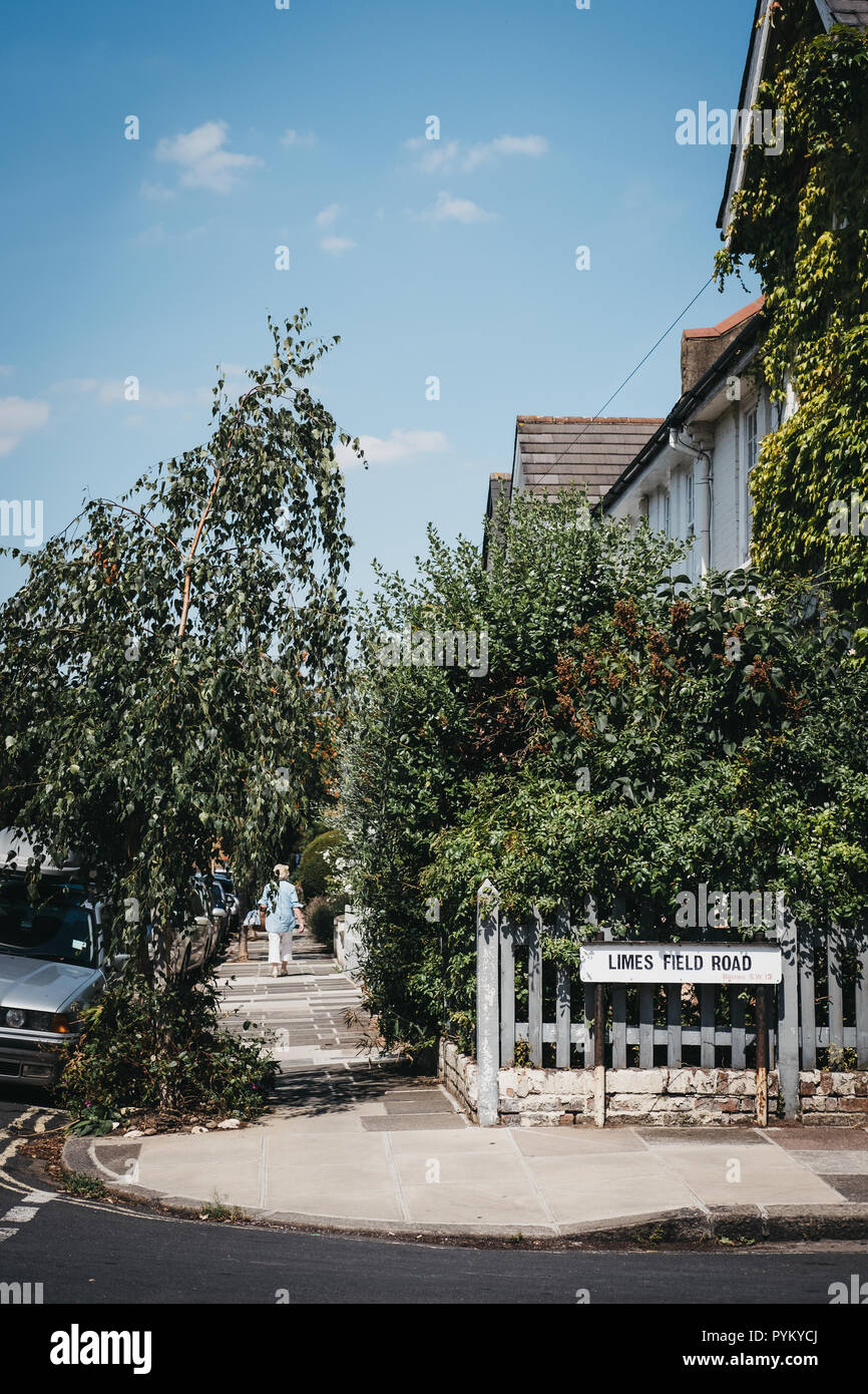 Vista posteriore della donna non identificato a camminare su una strada di Barnes, Richmond, Regno Unito, su un giorno d'estate. Foto Stock