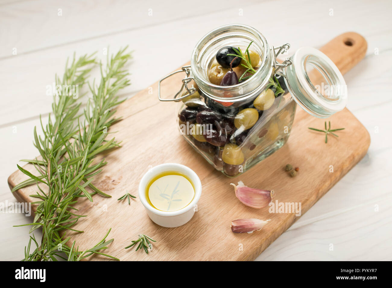 Varietà di olive marinate in un vaso. Aglio, rosmarino, olio d'oliva e spezie. Stile rustico Foto Stock