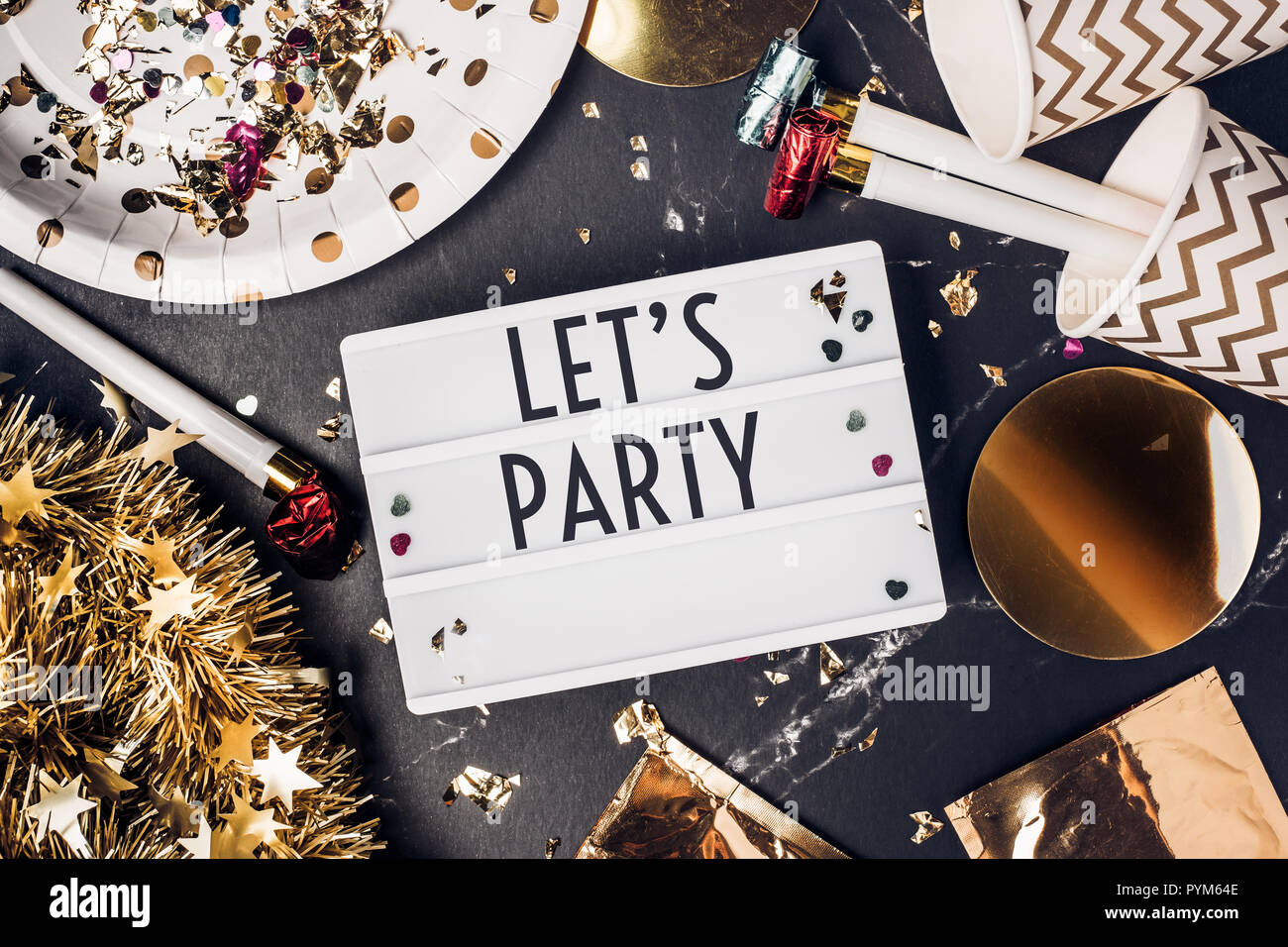 Andiamo a parte sulla scatola di luce con party cup,parte soffiante,tinsel,coriandoli.divertente festeggiare holiday party time table top view.anno nuovo e concetto di natale Foto Stock