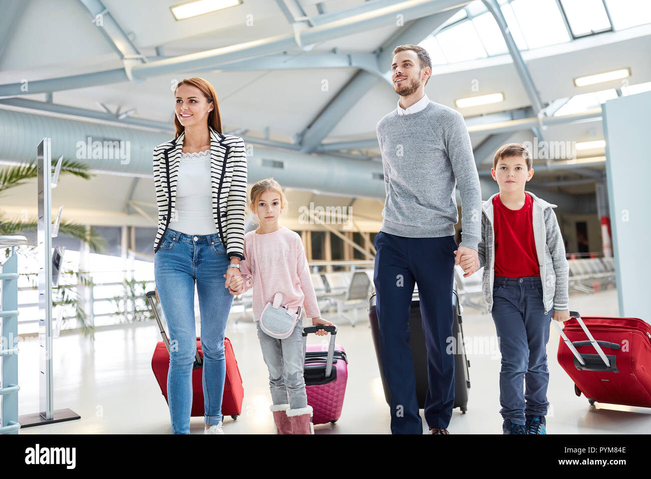 Famiglia con bambini e valigie in airport terminal vola insieme in vacanza Foto Stock