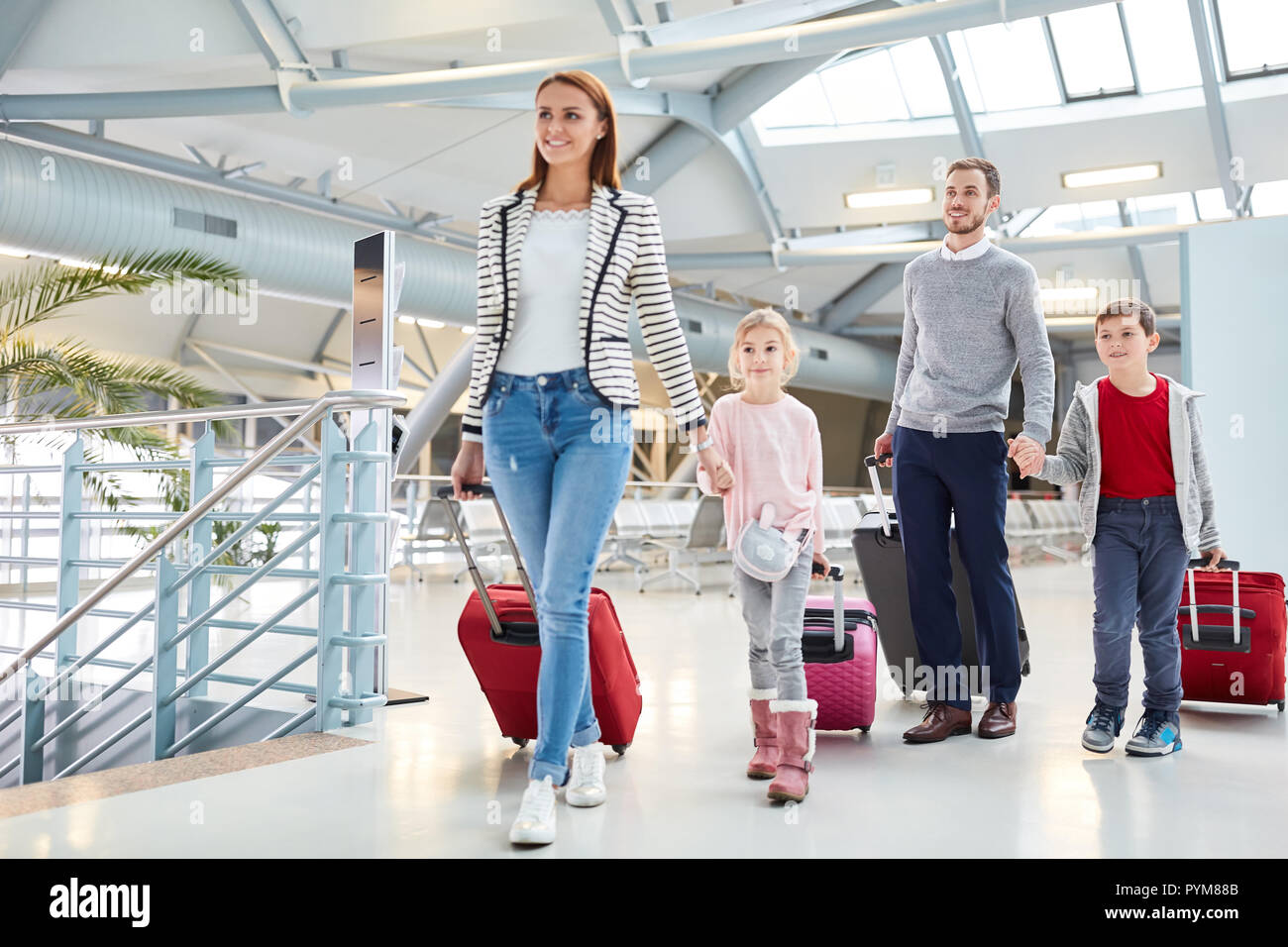 Famiglia con bambini e bagagli all'arrivo dopo il volo nel terminal dell'aeroporto Foto Stock