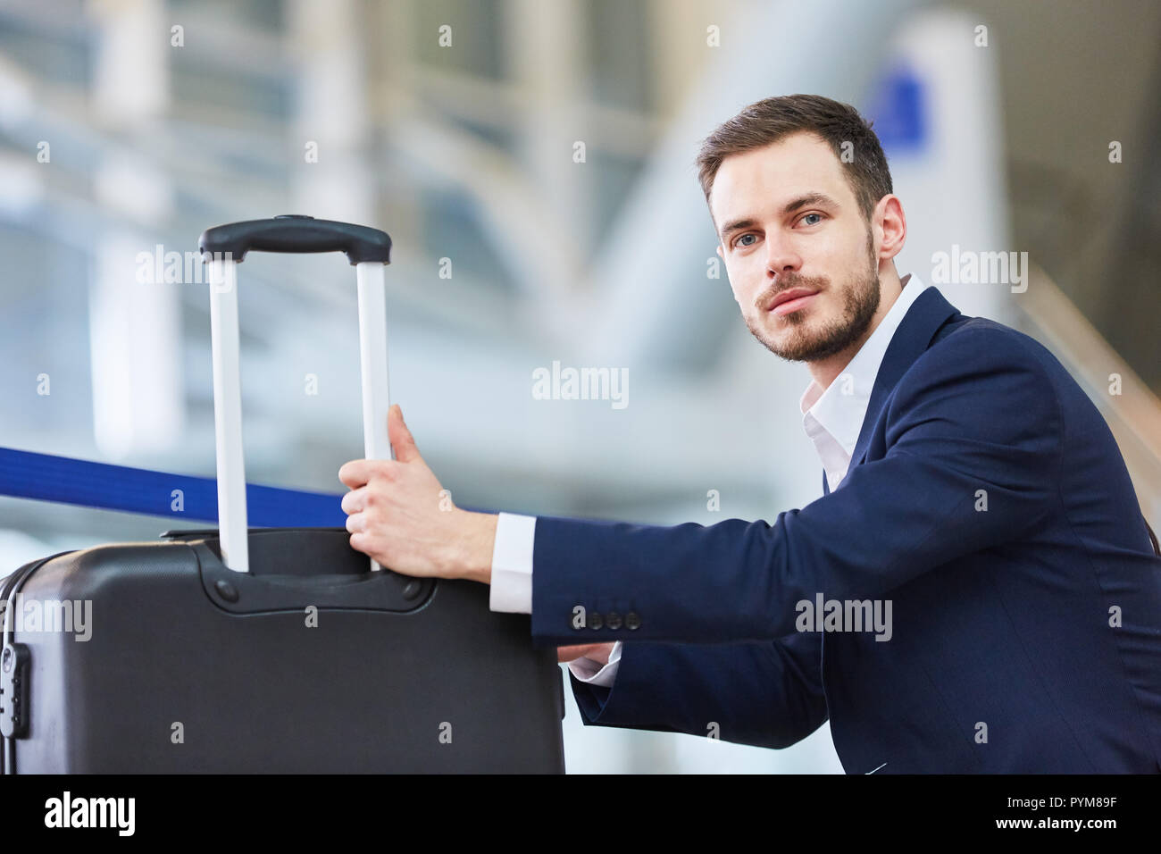 Imprenditore come un passeggero con trolley attende nel terminal dell'aeroporto di partenza Foto Stock