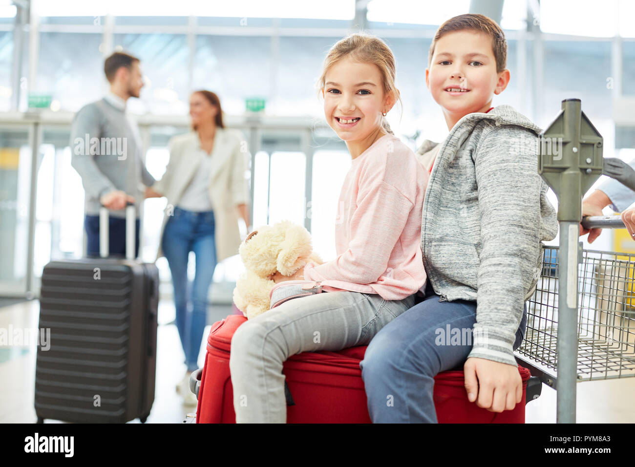 I gemelli sono bambini guardando in avanti per una vacanza in famiglia nel terminal dell'aeroporto Foto Stock