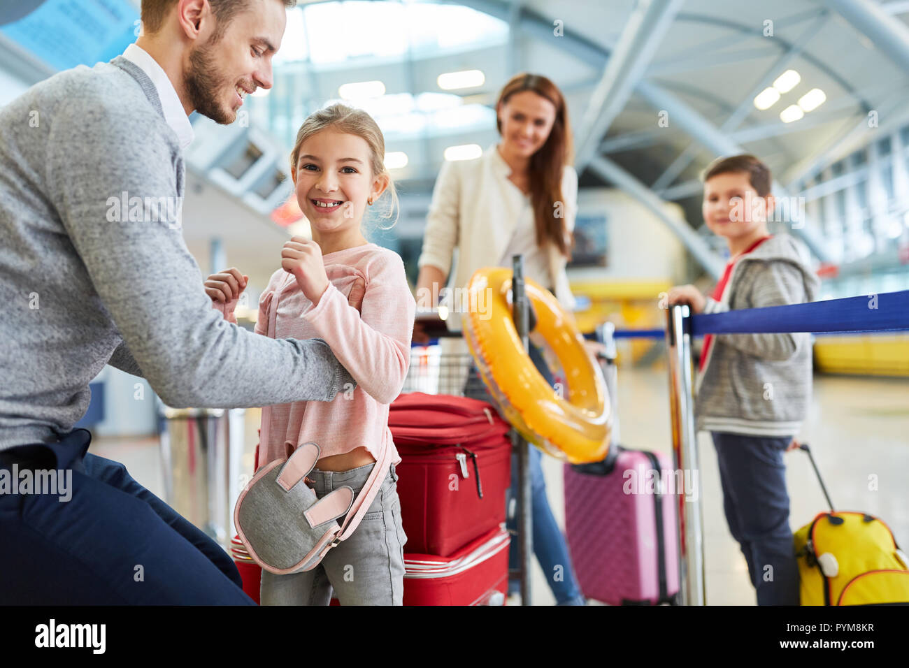 Il padre e la sua famiglia con due bambini nel terminal dell'aeroporto volare in vacanza Foto Stock