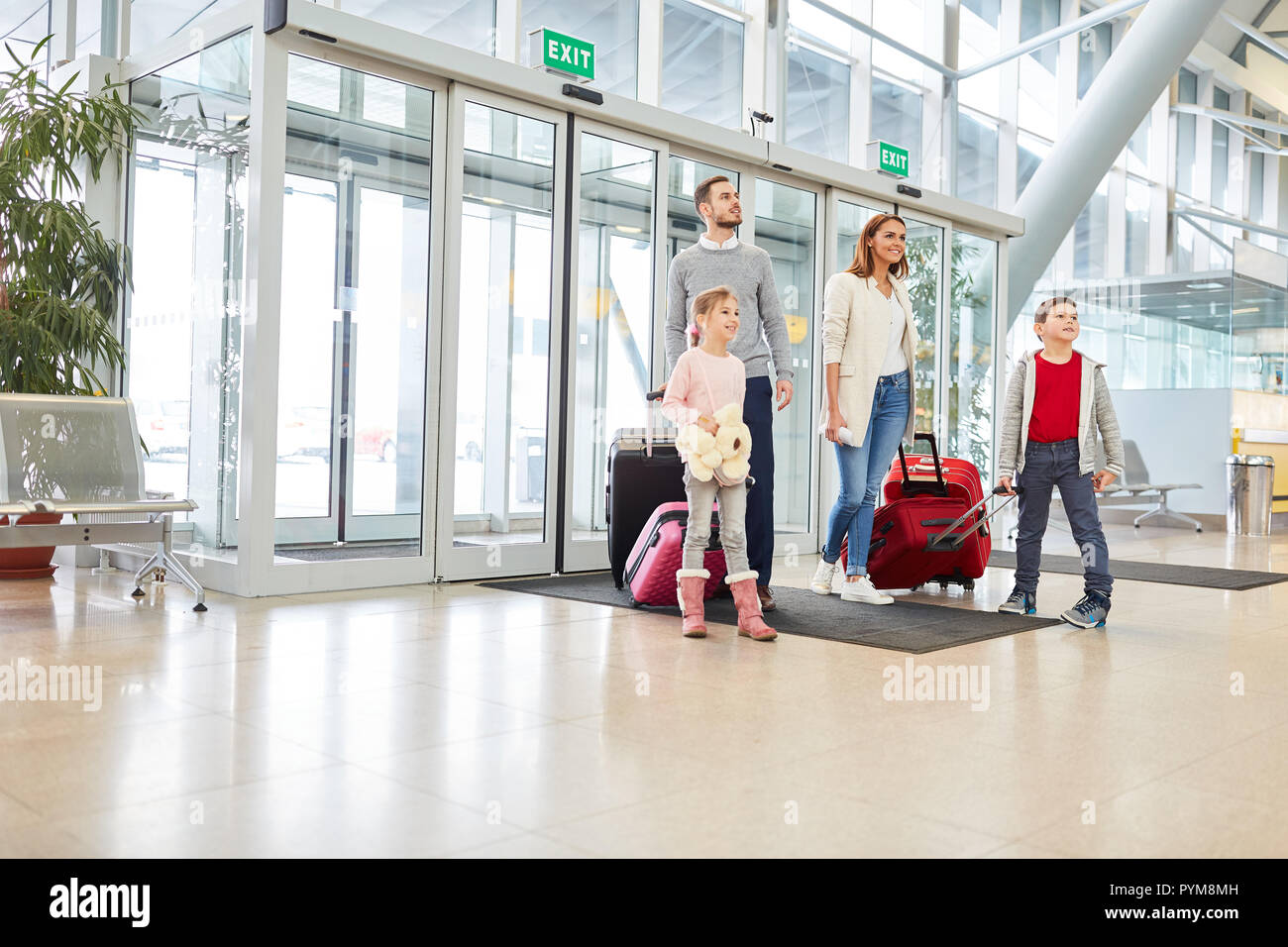 Famiglia con due bambini e bagagli in aeroporto è impaziente di vacanza Foto Stock