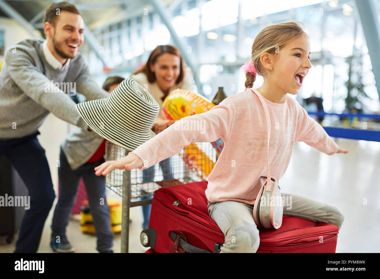 Ragazza ridere e famiglia nel terminal dell'aeroporto sono impaziente di vacanza Foto Stock