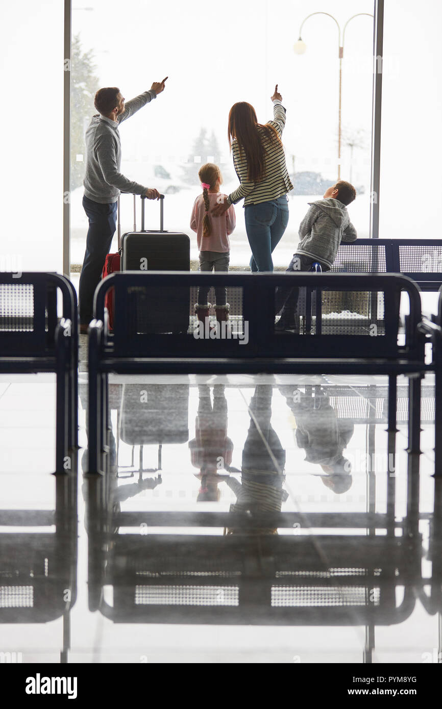 La famiglia e i bambini nella sala d'attesa dell'aeroporto ​​the nella finestra Attesa per il volo di coincidenza Foto Stock