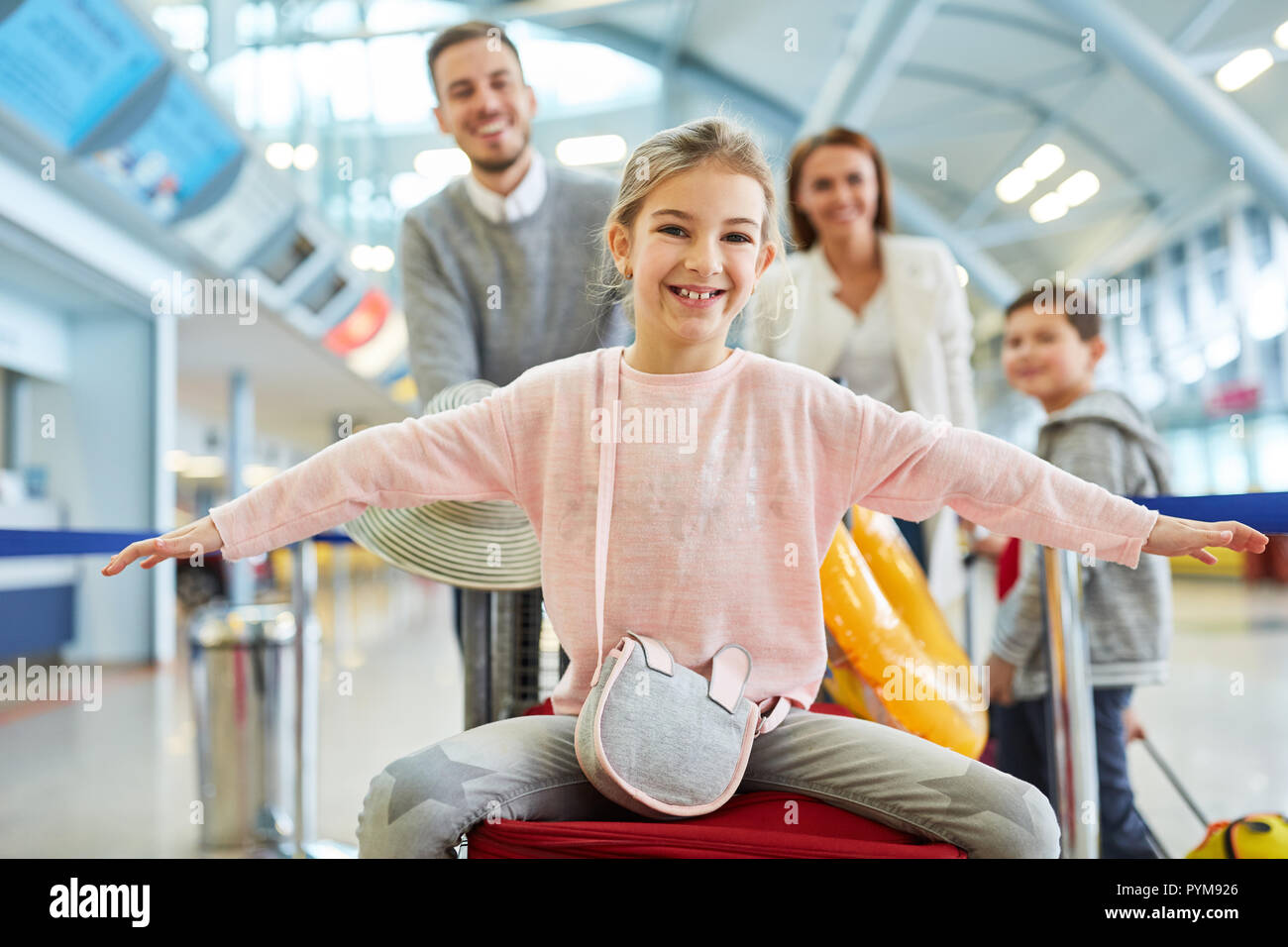 Felice la ragazza e la famiglia sul modo per vacanza nel terminal dell'aeroporto Foto Stock
