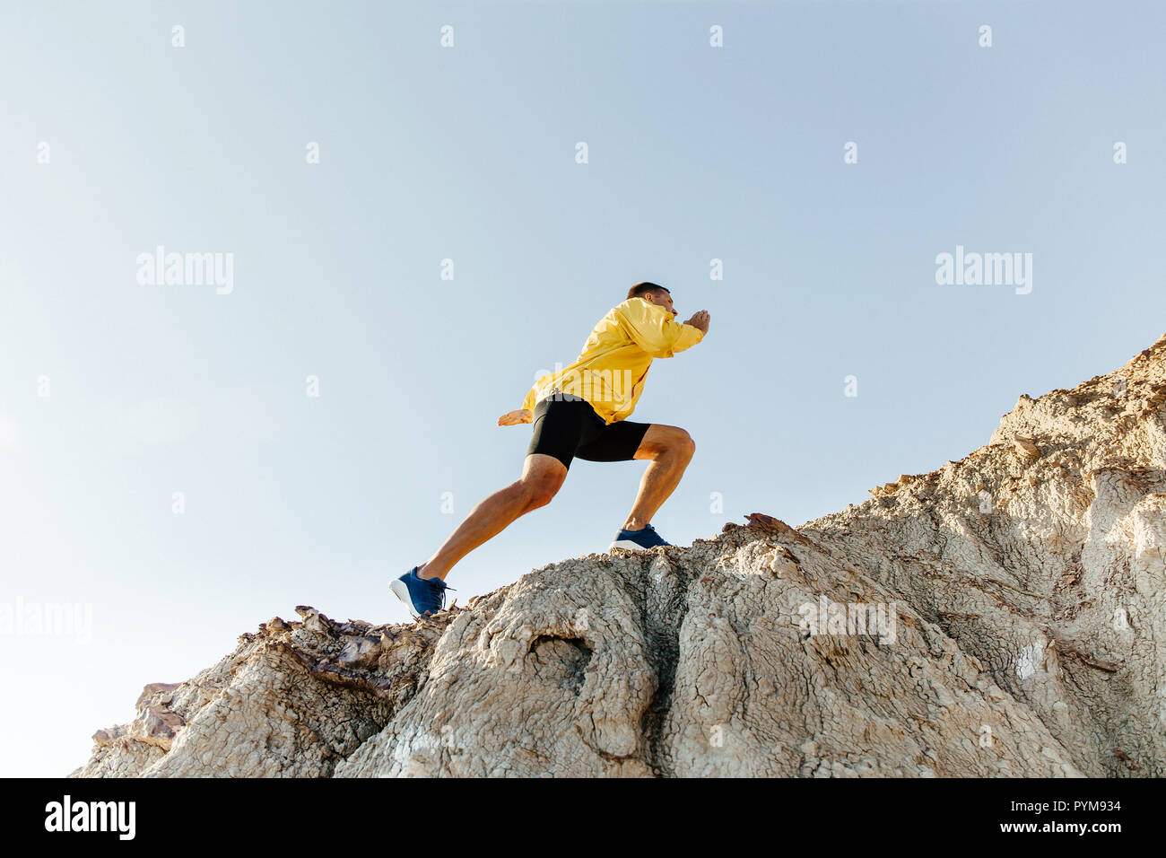 Concetto di superare le difficoltà. l uomo in abbigliamento sportivo arrampicata ripida montagna Foto Stock