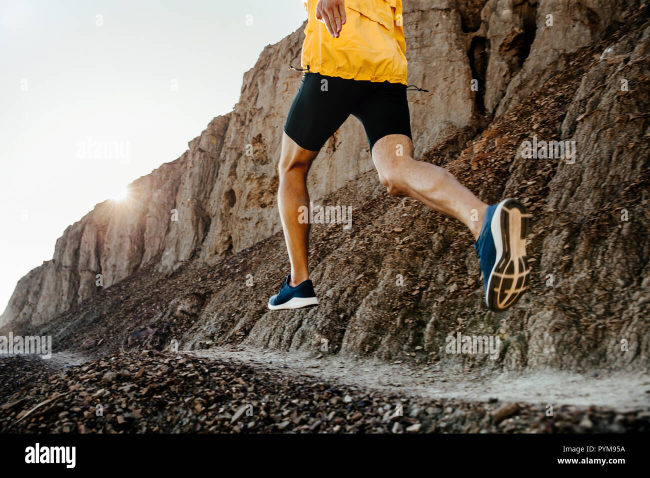L'uomo atleta che corre sul sentiero di montagna in presenza di luce solare Foto Stock