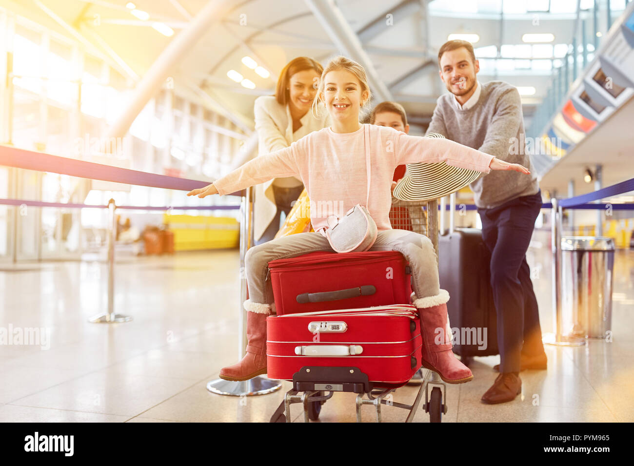 La famiglia felice con i bambini e con i bagagli all'aeroporto sulla strada per le vacanze estive Foto Stock