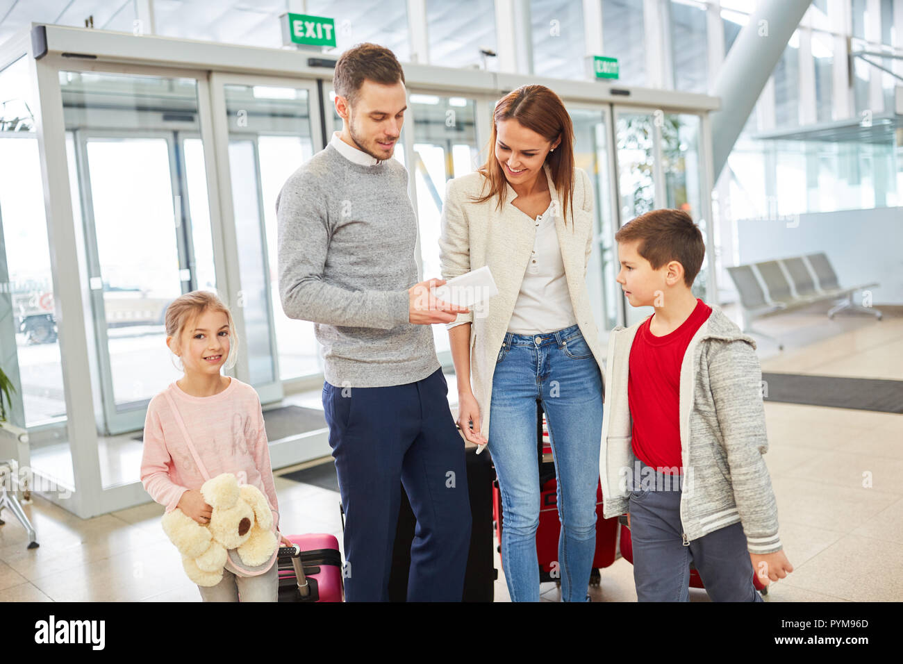 Famiglia con due bambini nel terminal dell'aeroporto è impaziente di viaggiare in vacanza Foto Stock