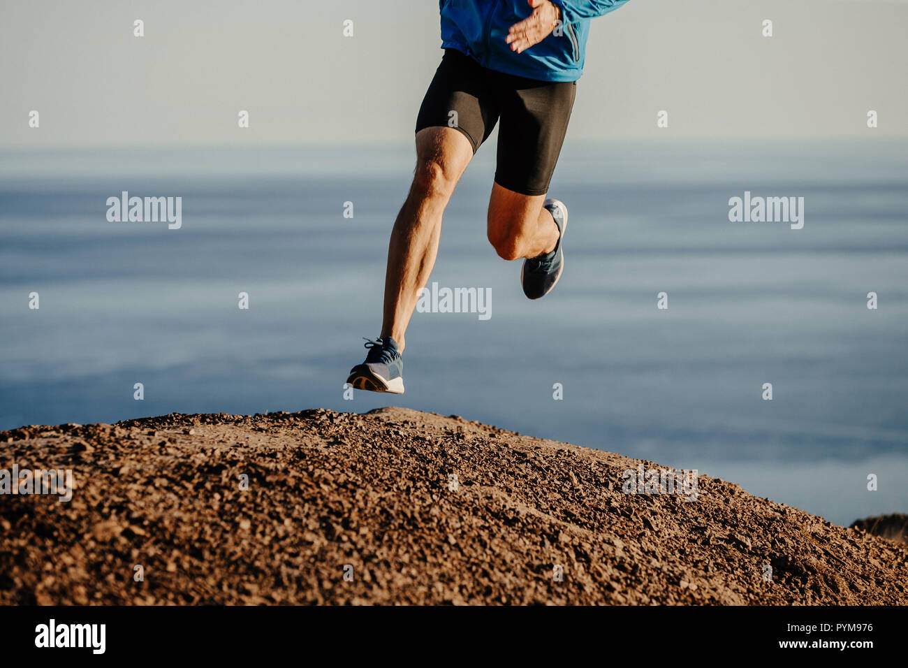 Atleta runner acceso in salita sulla montagna sullo sfondo di un mare Foto Stock