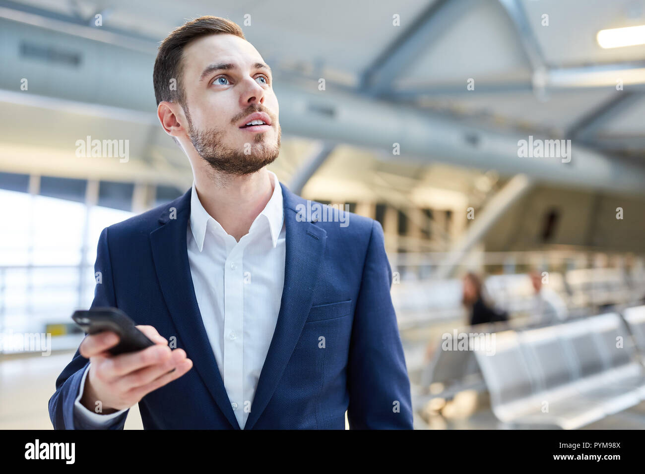 Uomo d affari con lo smartphone in aeroporto è sorpreso da un messaggio Foto Stock