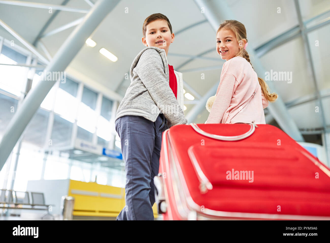 Fratelli e sorelle nel terminal dell'aeroporto con la valigia insieme formano un piano di viaggio durante le vacanze Foto Stock