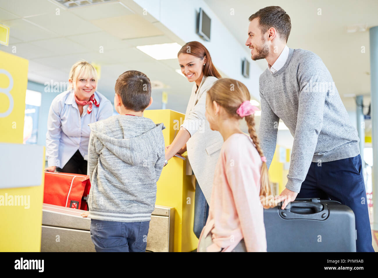 La famiglia e i bambini in il terminal aeroportuale presso il banco per il check-in sulla strada in vacanza Foto Stock