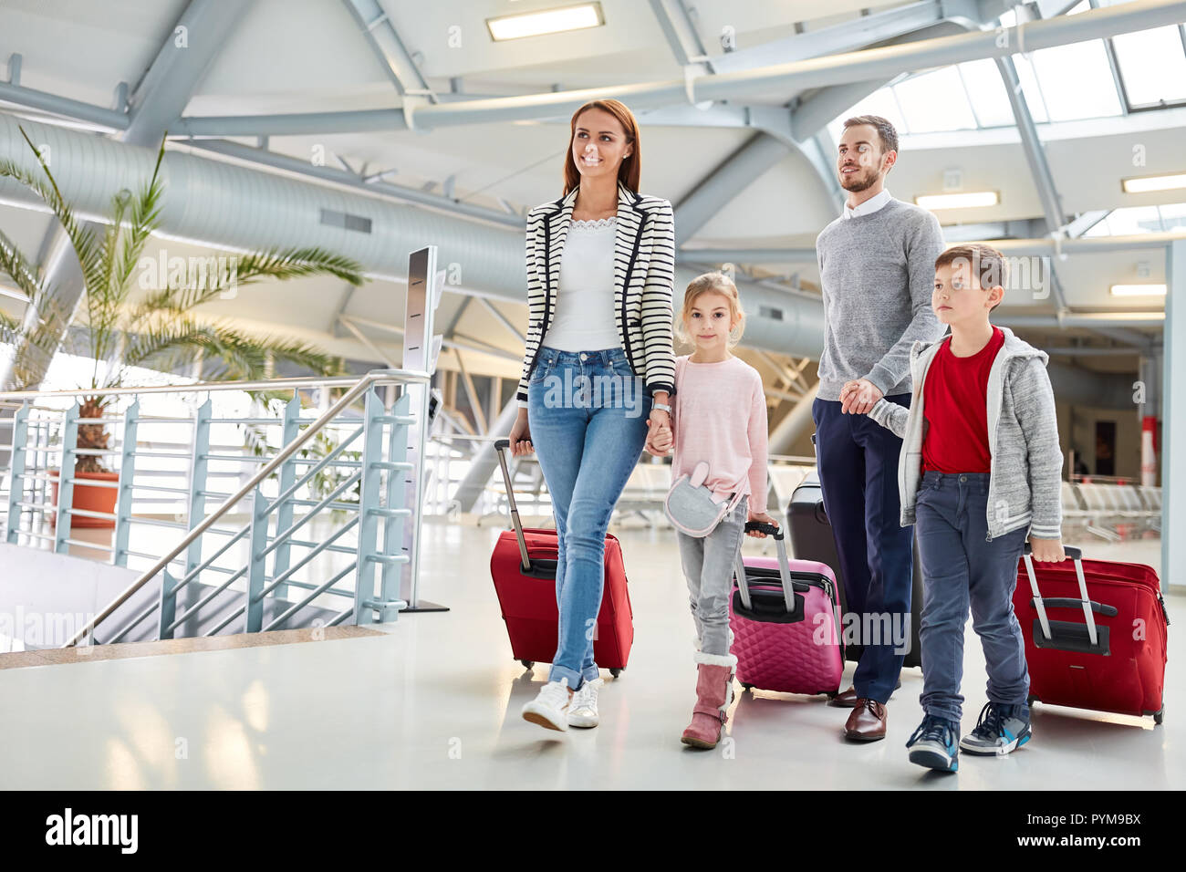Famiglia con figli e bagagli sulla strada in vacanza nel terminal dell'aeroporto Foto Stock