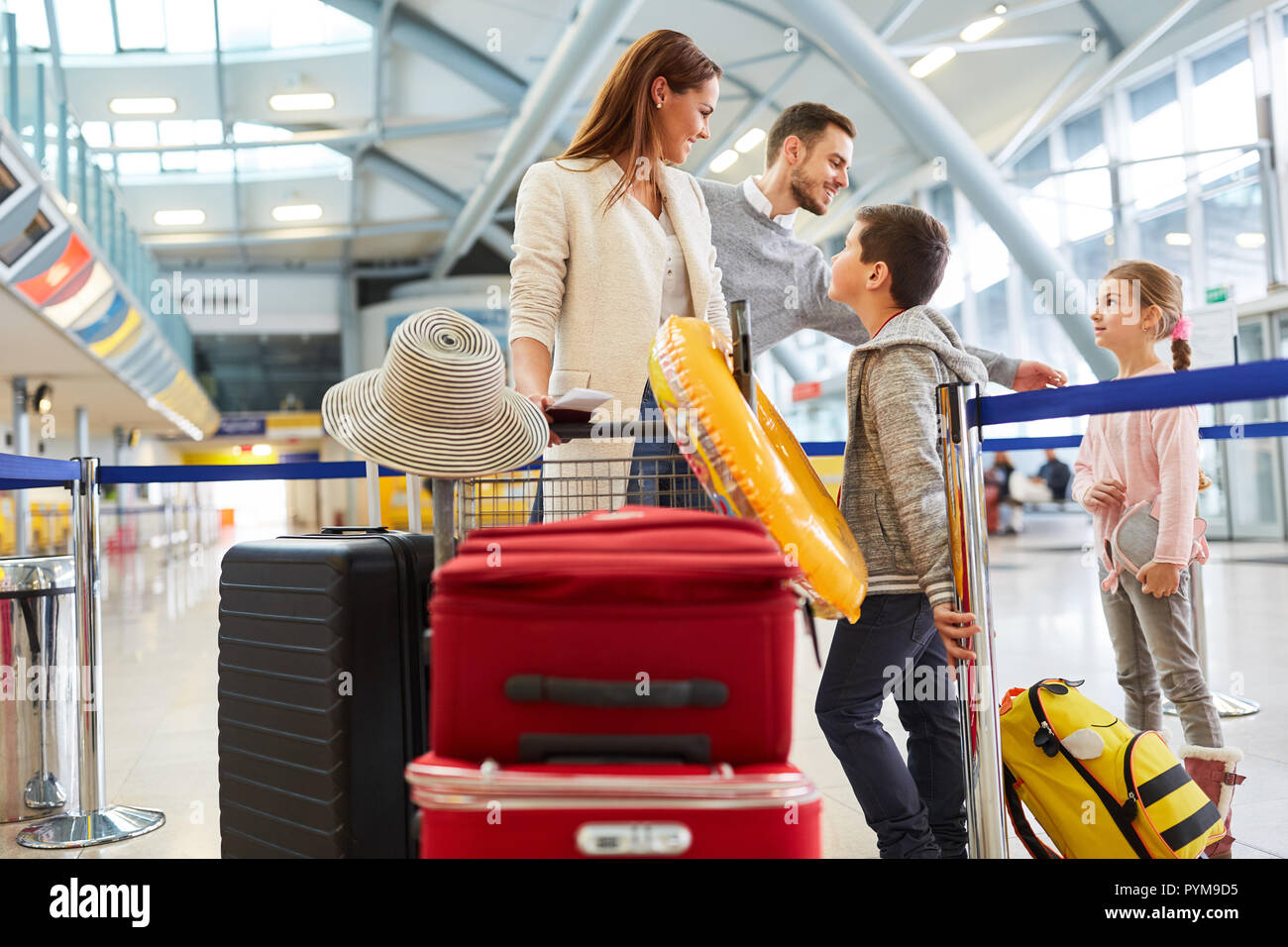 La famiglia felice con un sacco di bagagli in aeroporto è in viaggio in vacanze estive Foto Stock