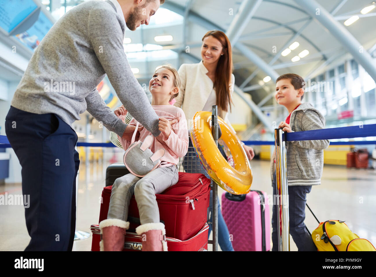 La famiglia felice e due bambini nel terminal dell'aeroporto è guardare avanti per la vacanza in famiglia Foto Stock