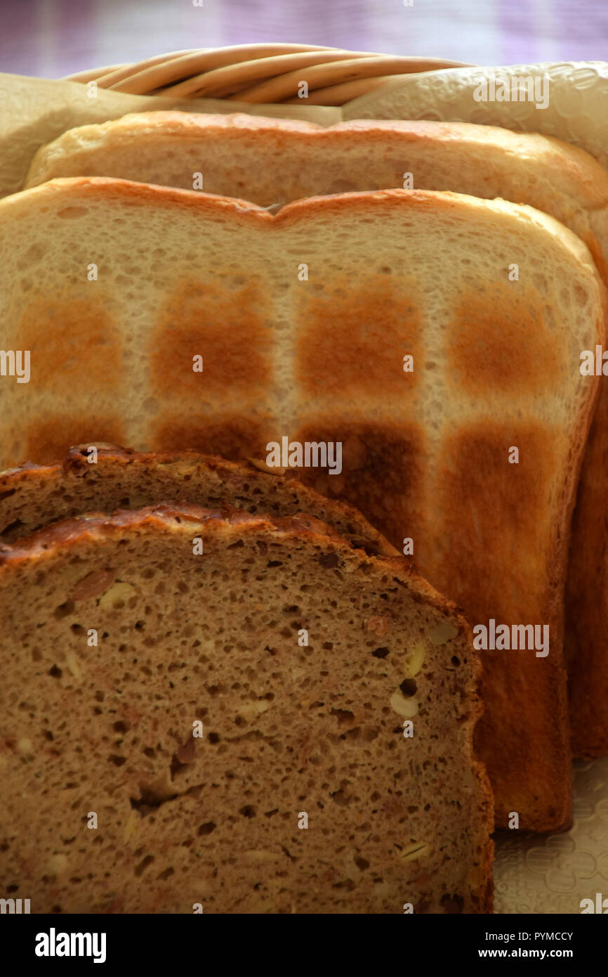 Fresco e gustoso pane tostato e pane di grano, diversi tipi di pane in un cestino del pane per la colazione o per il tè pomeridiano Foto Stock