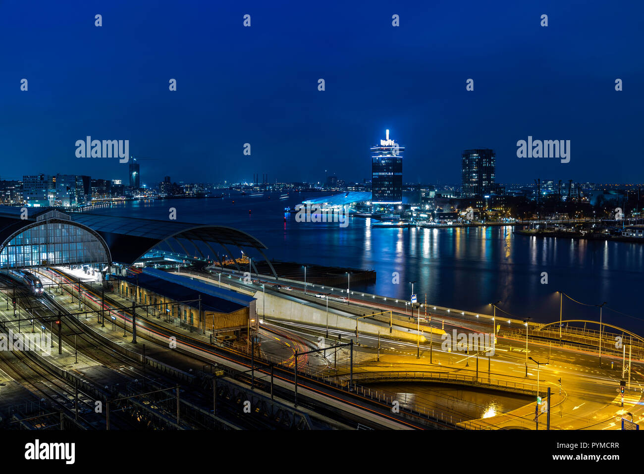 Vista del Amsterdam stazione ferroviaria e il fiume Amstel di notte, Paesi Bassi Foto Stock