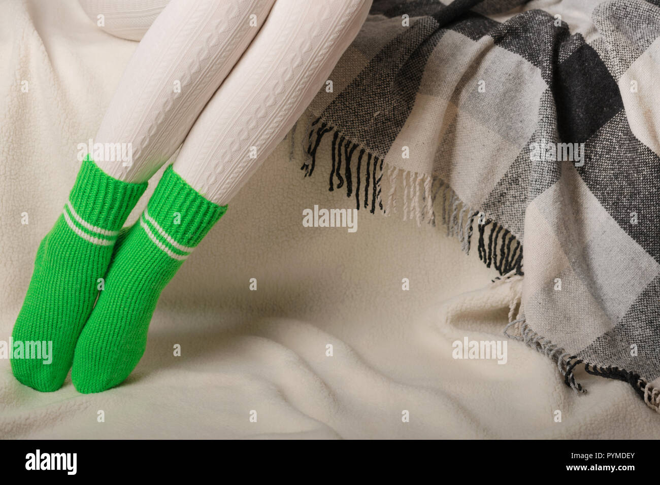 Gambe femmina in caldo a maglia bianco collant e calzini verdi su sfondo bianco fatta di pelliccia. Foto Stock