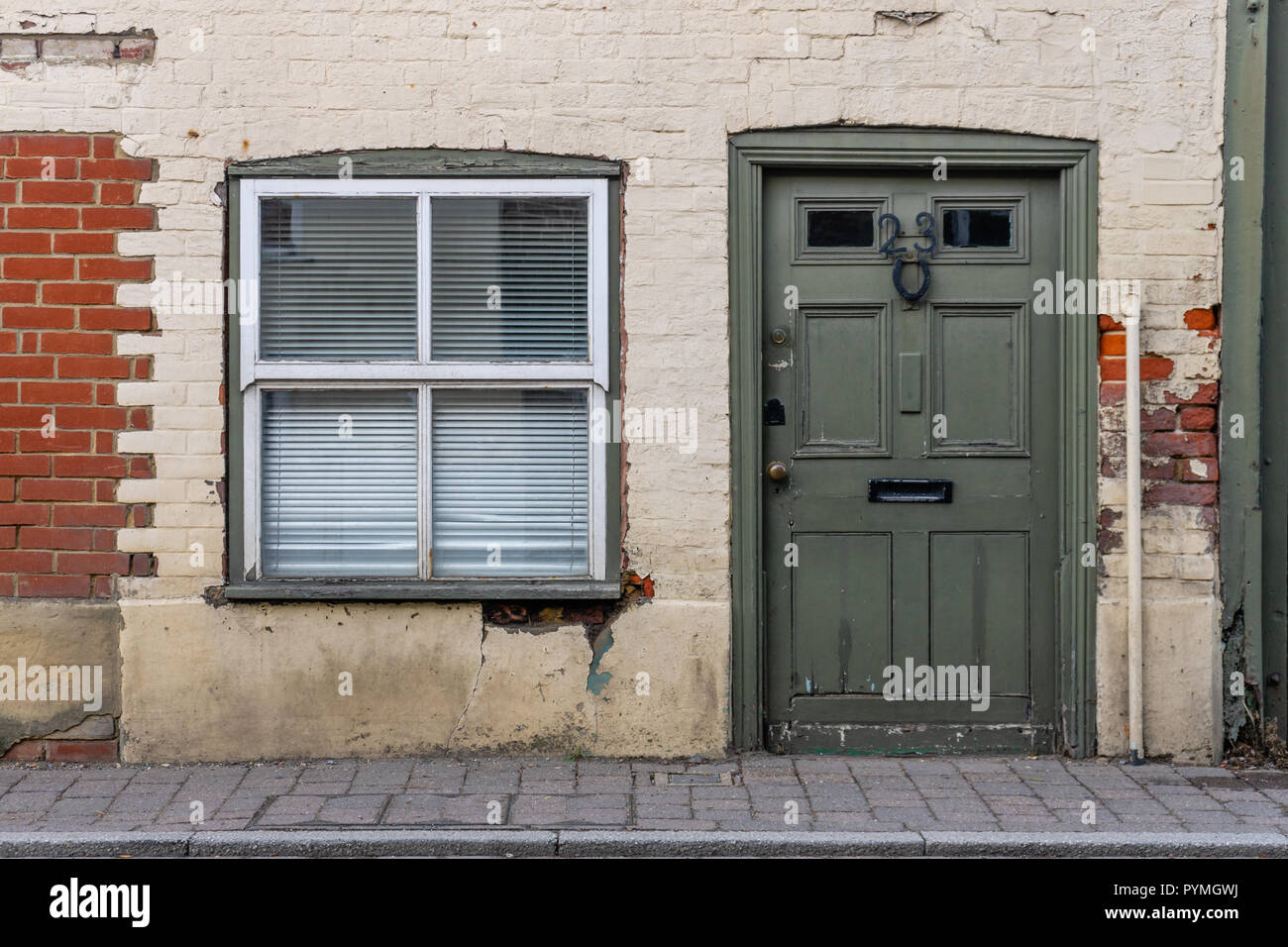 Facciata di una vecchia casa con finestra e una porta verde in Fordingbridge, Hampshire, Inghilterra, Regno Unito Foto Stock