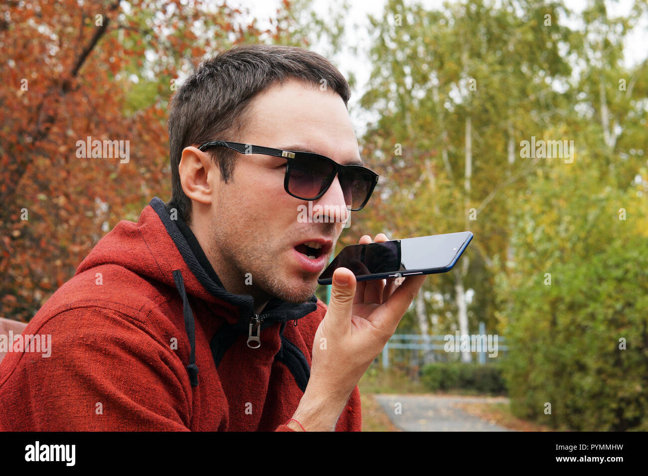 La registrazione sul dittafono. Tempo libero, la tecnologia, la comunicazione e il concetto di persone - hipster uomo utilizzando il comando vocale registratore o chiamando sullo smartphone a Foto Stock