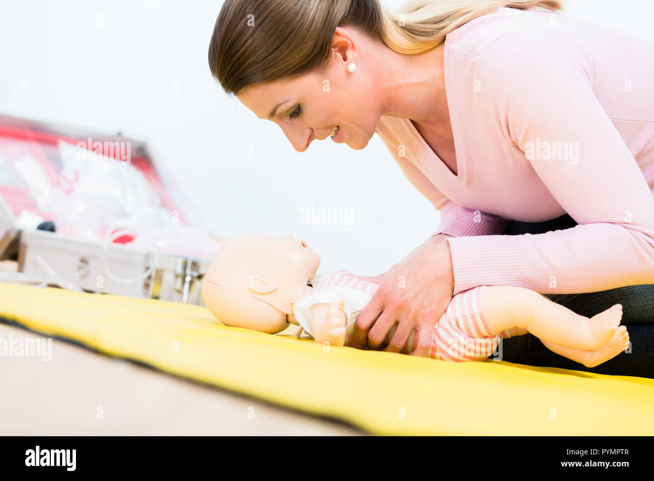 La donna nel corso di primo soccorso pratica di rilancio del neonato sulla baby d Foto Stock