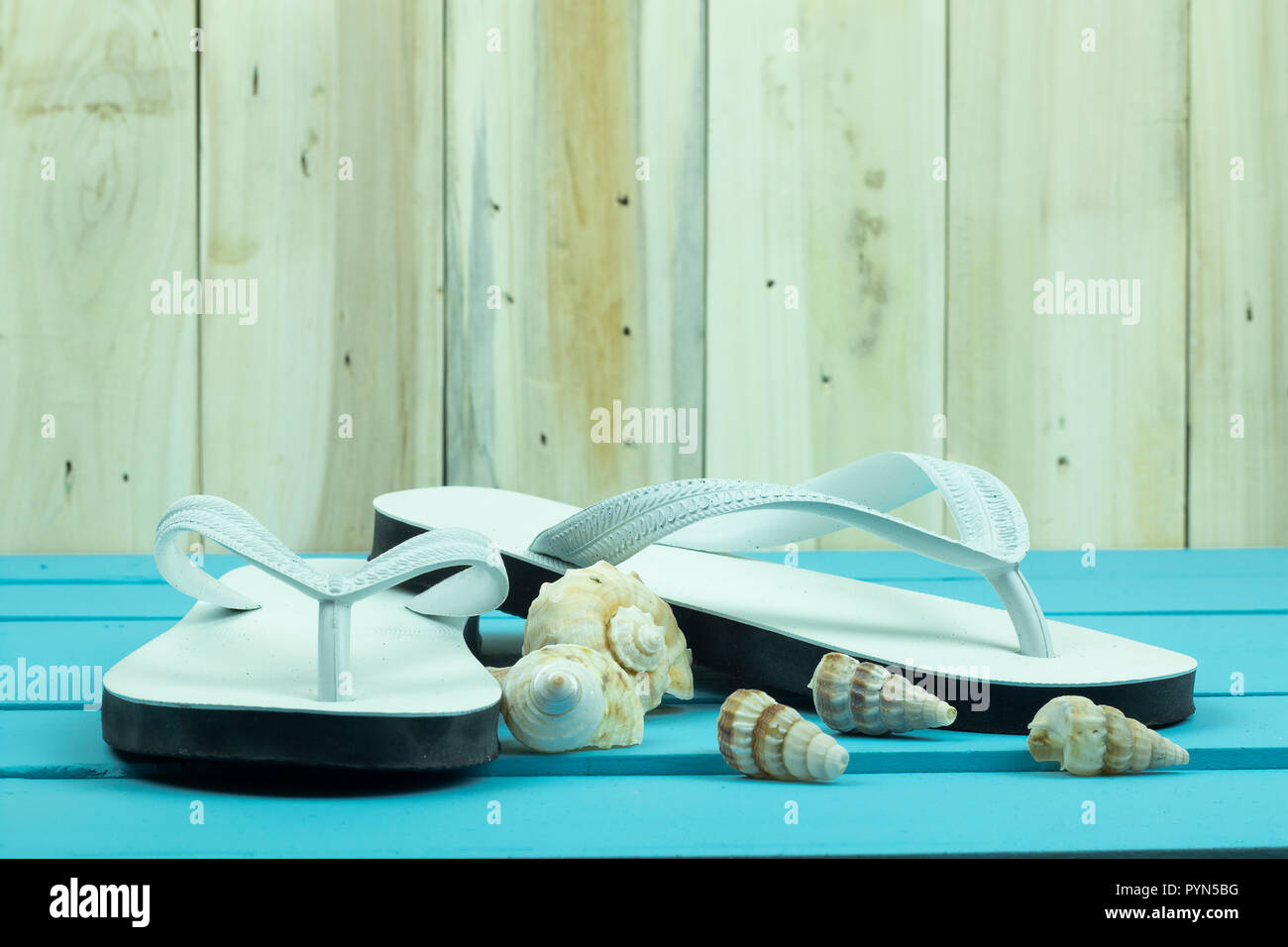 White flip flop con shellfishs sull'azzurro del tavolo di legno. Foto Stock