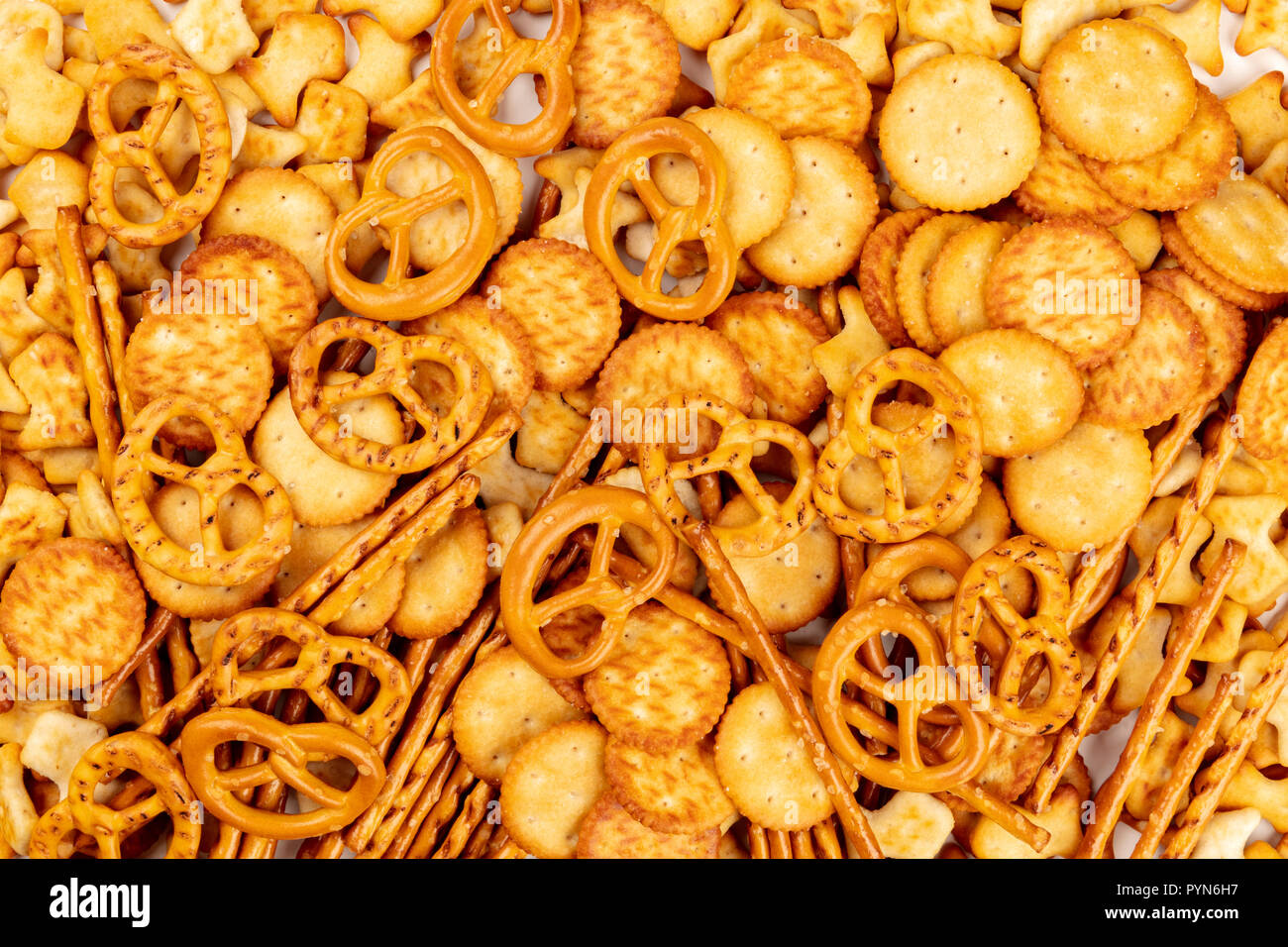 Una foto di un assortimento di sale crackers, bastoncini, salatini e pesci, ripresa dall'alto su sfondo bianco Foto Stock