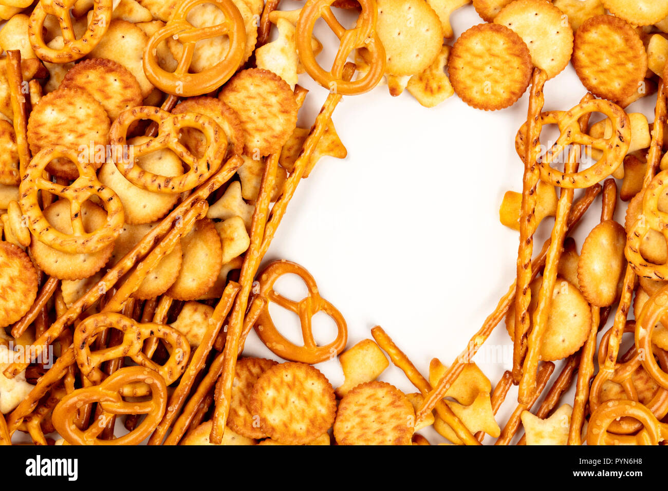 Una foto di un assortimento di sale crackers, bastoncini, salatini e pesci, ripresa dall'alto su uno sfondo bianco, con un telaio per lo spazio di copia Foto Stock