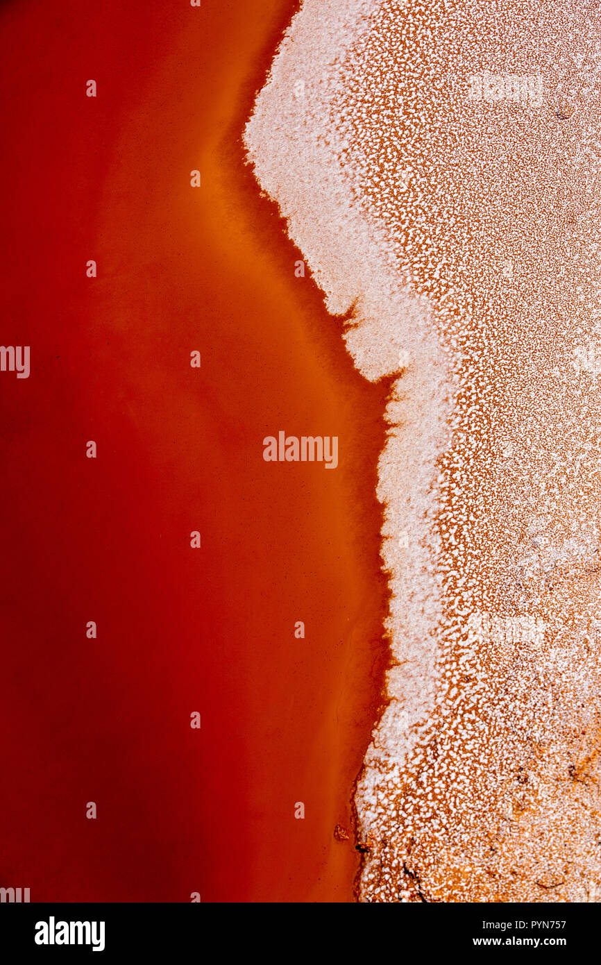 Nahaufnahme eines Salzbeckens in Rot-Oranger Farbe mit Salzkristallen - abstrakte Formen -aufgenommen in einem Salzbecken in Perù, Südamerika Foto Stock