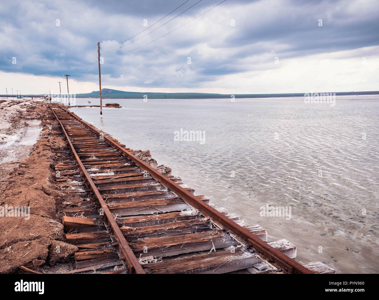Rusty razy rotaie e traversine marcio coperto di sale sulla vecchia ferrovia tracce su una collinetta a miniere di sale vicino lago di salamoia. Foto Stock
