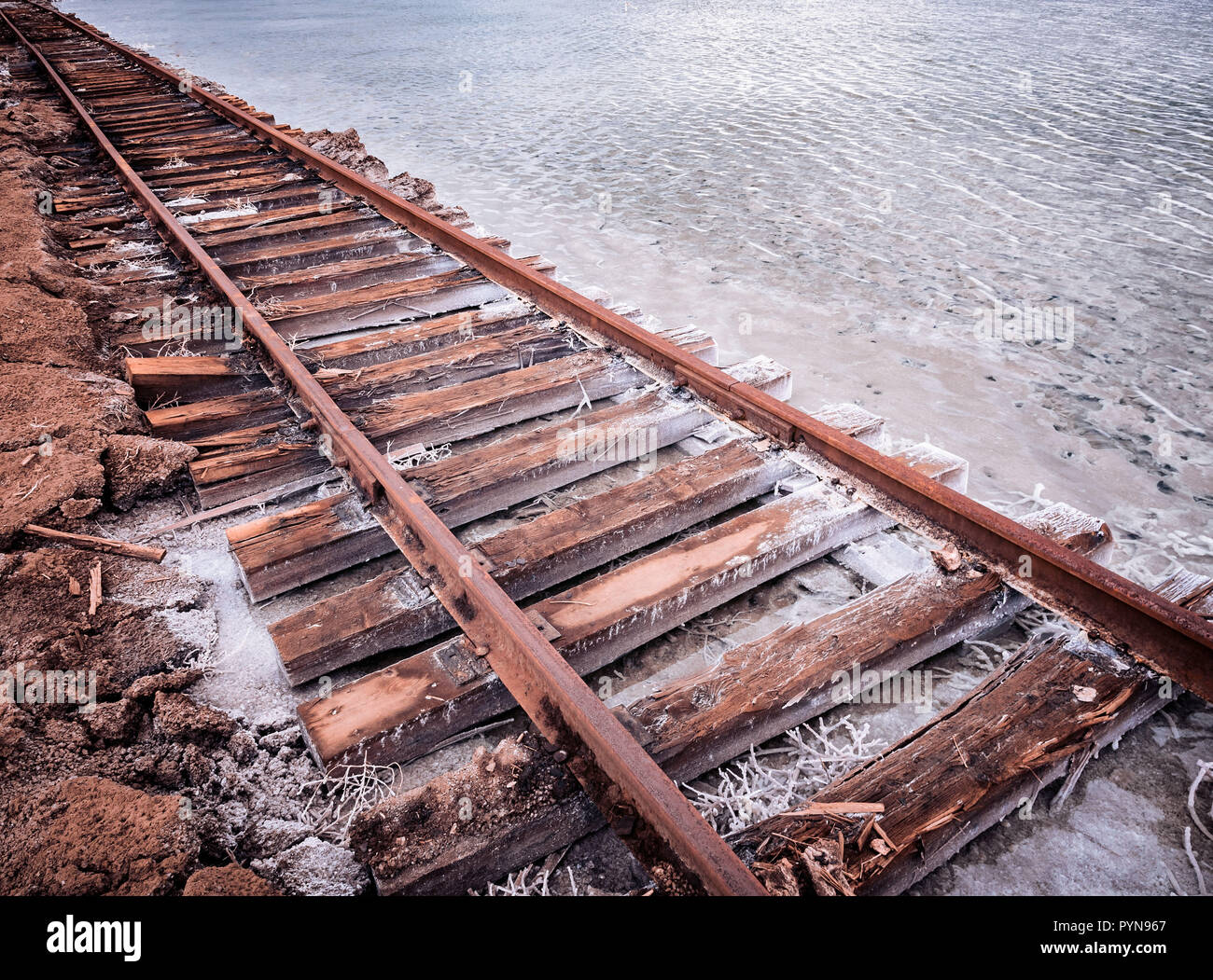 Rusty razy rotaie e traversine marcio coperto di sale sulla vecchia ferrovia tracce su una collinetta a miniere di sale vicino lago di salamoia. Foto Stock