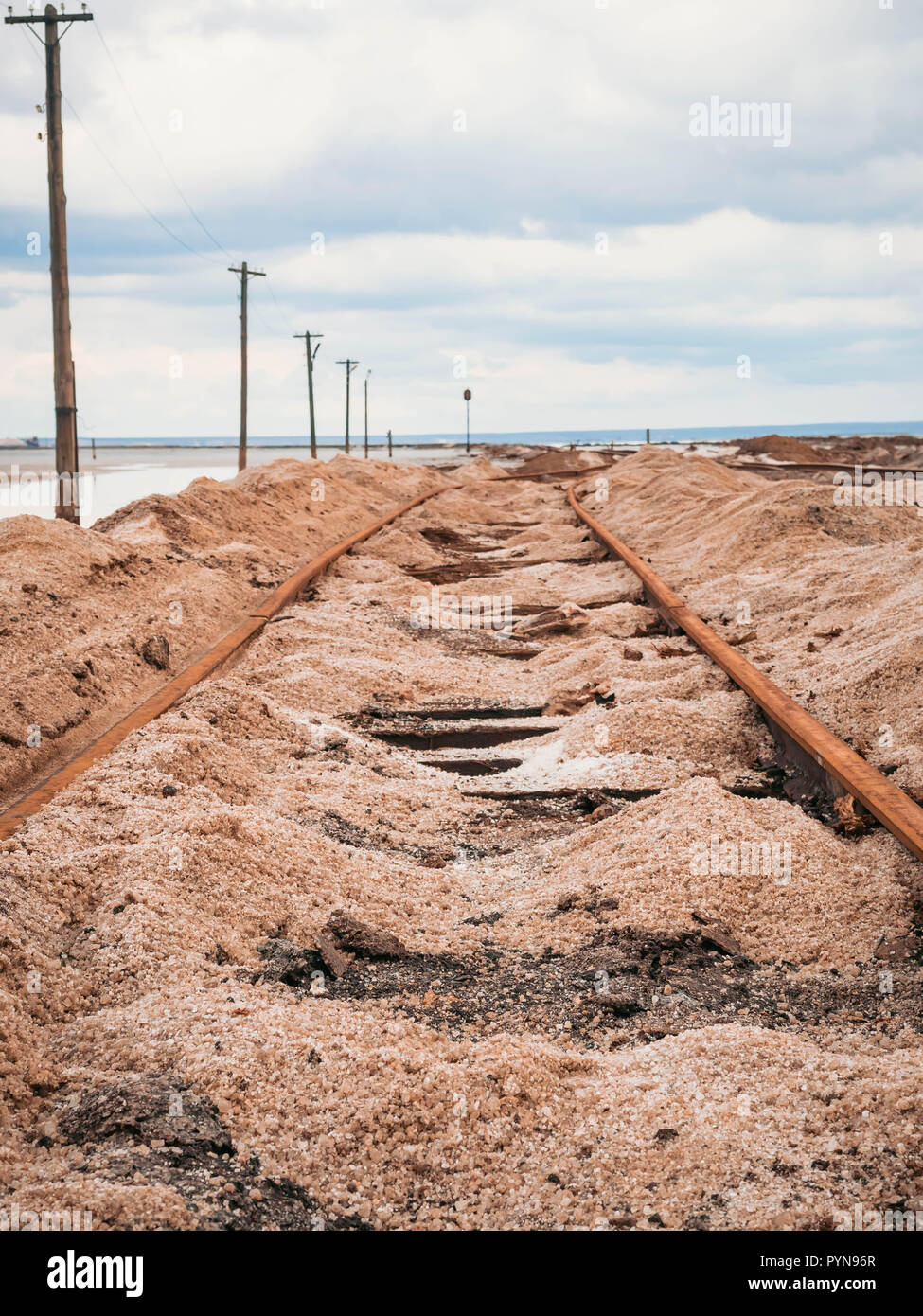 Rusty razy rotaie e traversine marcio coperto di sale sulla vecchia ferrovia tracce su una collinetta a miniere di sale vicino lago di salamoia. Foto Stock