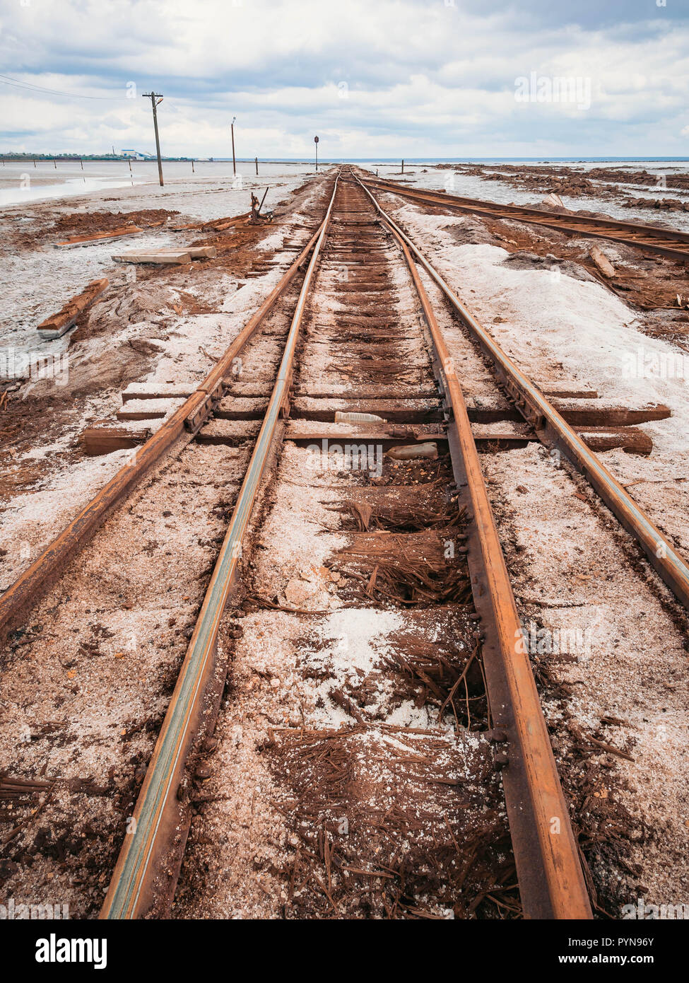 Rusty razy rotaie e traversine marcio coperto di sale sulla vecchia ferrovia tracce su una collinetta a miniere di sale vicino lago di salamoia. Foto Stock
