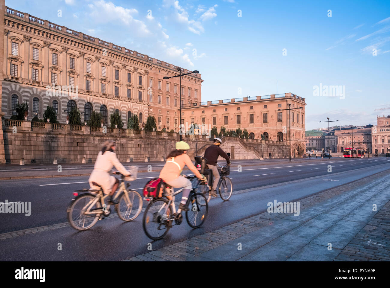 Tre eco friendly ciclisti utilizzare una bicicletta corsia sulla strada Skeppsbron al di fuori del Palazzo Reale, la Gamla Stan, Stoccolma, Svezia Foto Stock