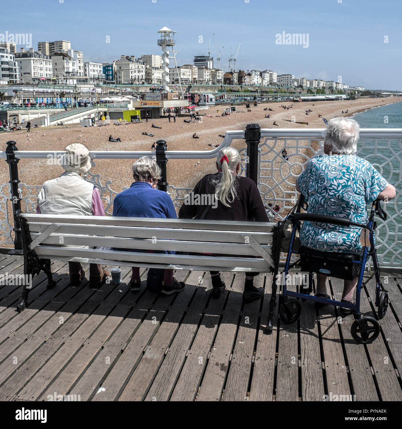 Persone sedute sul molo di Brighton Foto Stock