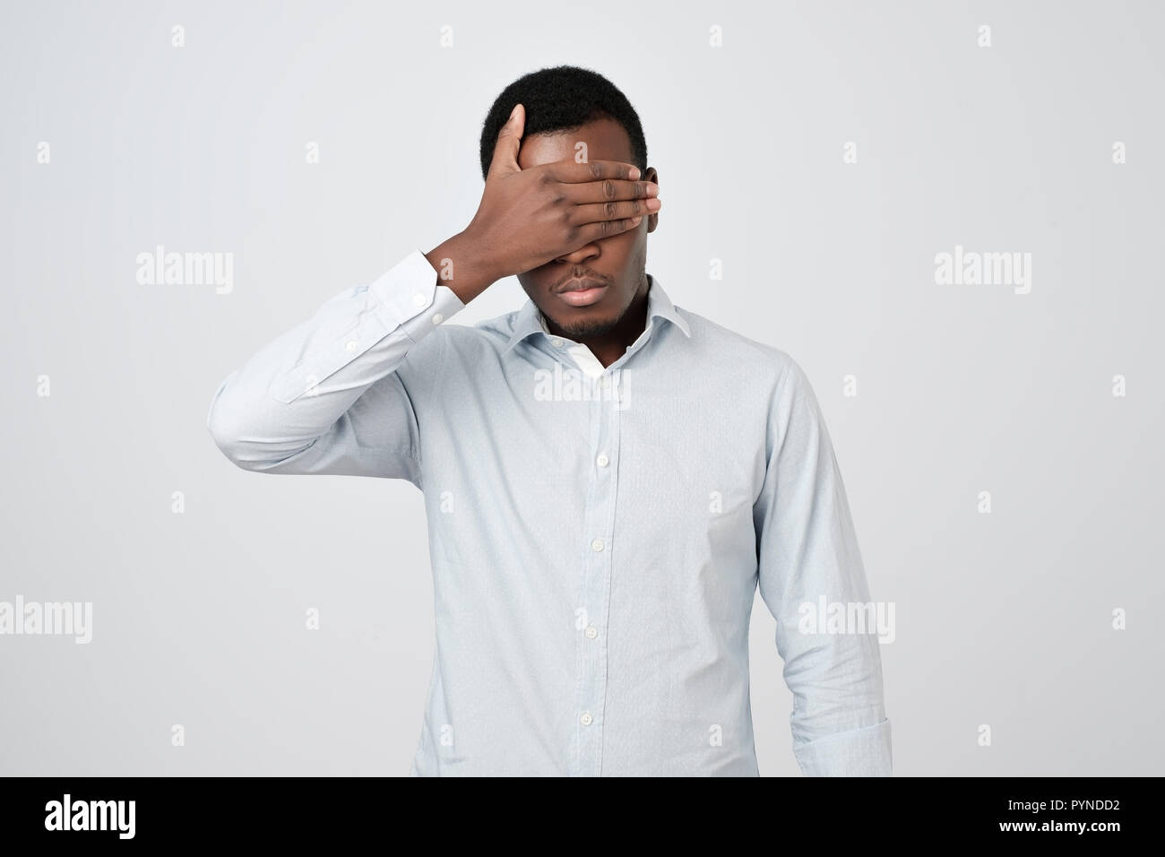 Oung african Uomo in camicia bianca che copre gli occhi Foto Stock