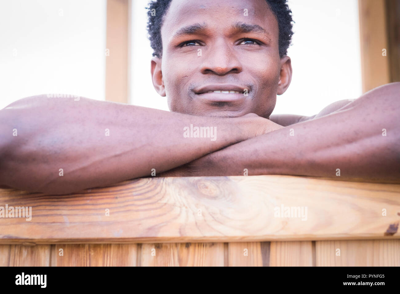 Bella black afro gara maschile etnica sorriso e rilassarvi su una barra di legno. close up ritratto di giovane popolo millenario di godere della vita e dell'età. Beautine Foto Stock