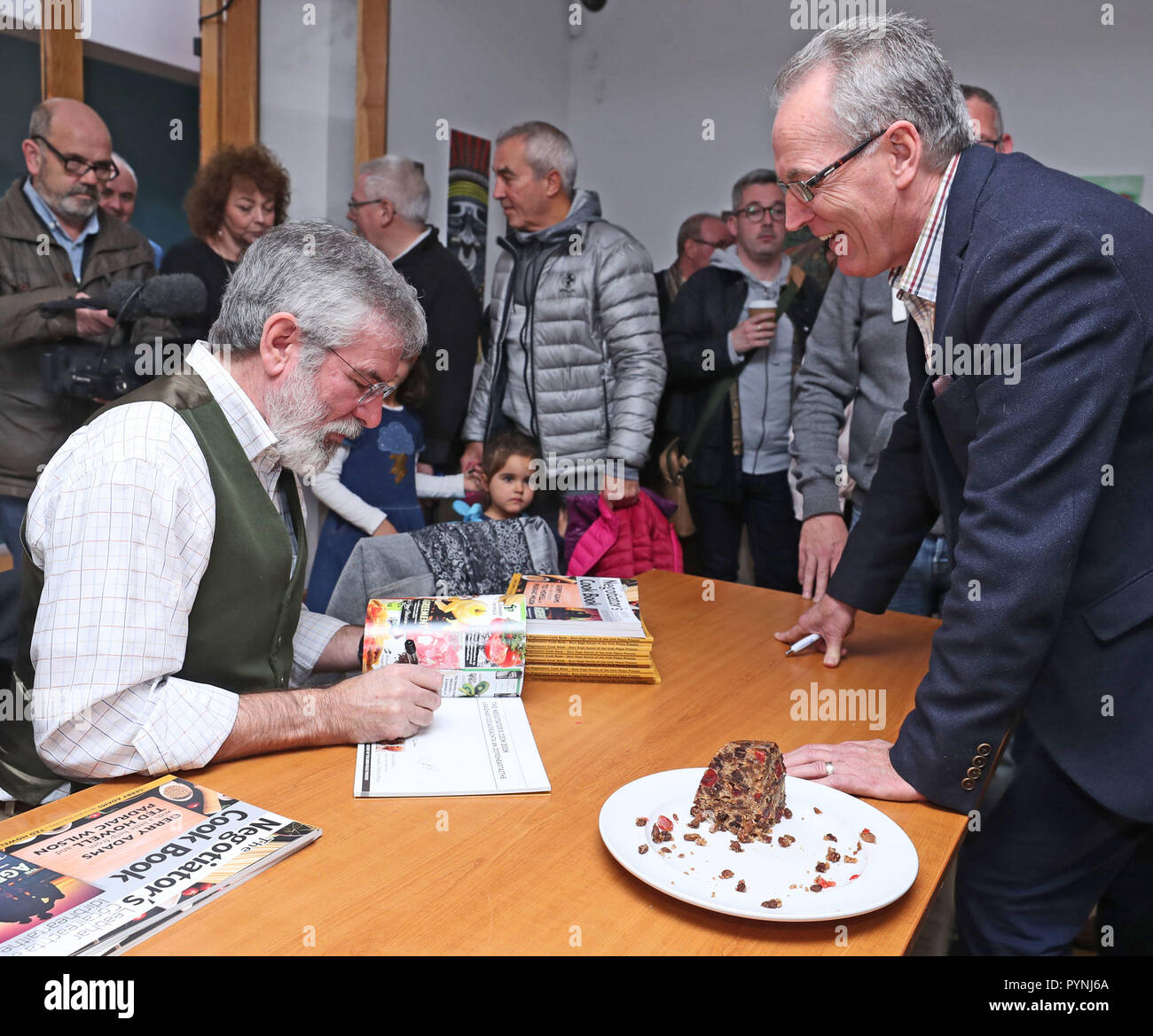L'ex leader del Sinn Fein Gerry Adams firma una copia del suo libro di ricette dal titolo 'il Cookbook' dei negoziatori' durante il suo lancio al Culturlann sulla Falls Road a Belfast. Foto Stock