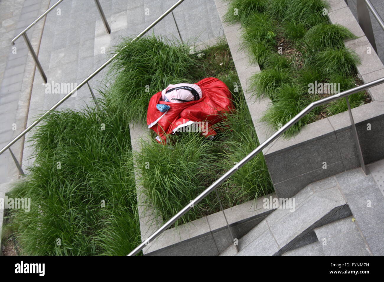 Una ragazza in abito rosso i performa performance artistica in uno spazio pubblico. Molto elegante e brave le prestazioni nel centro della città di Milano. Foto Stock