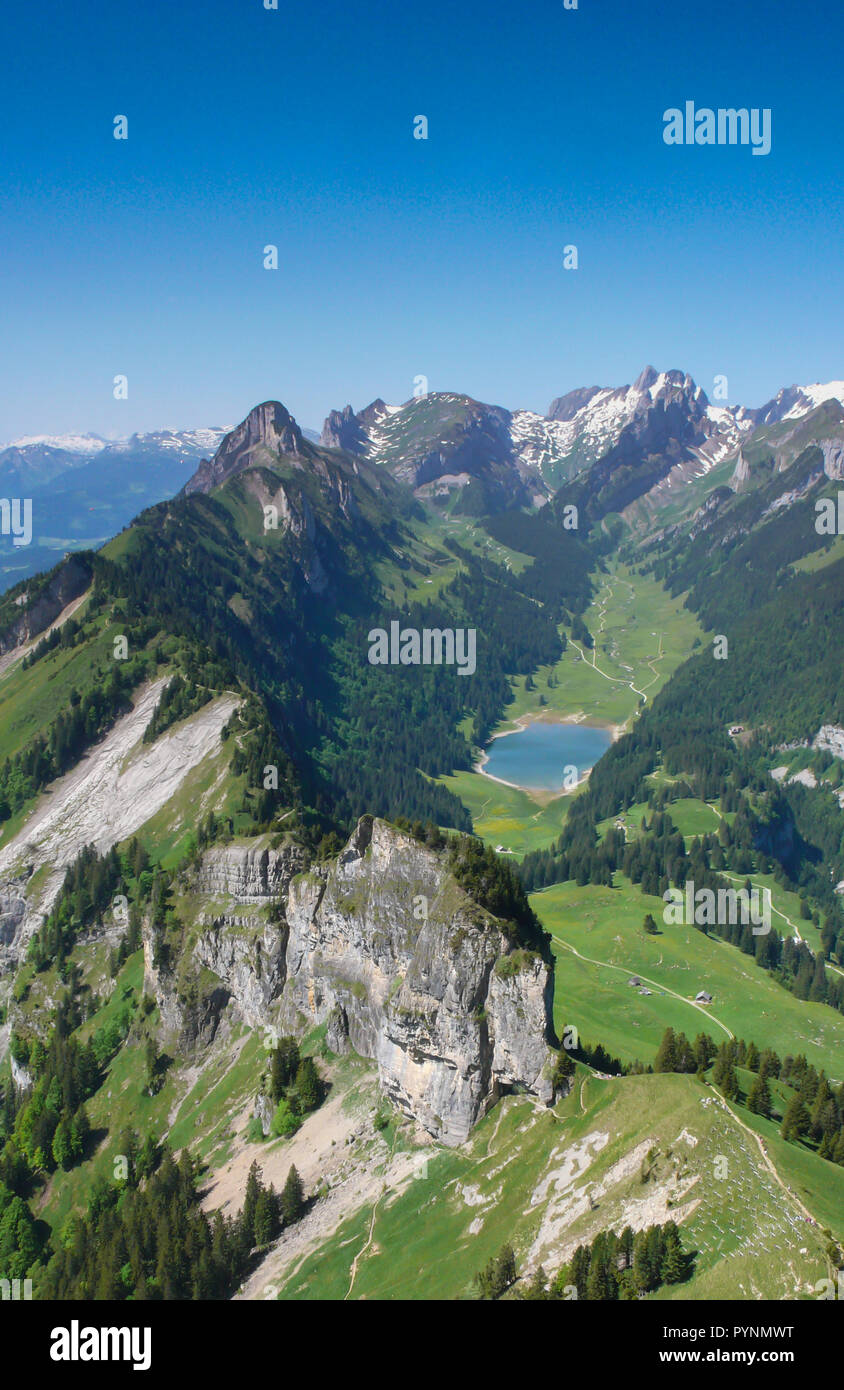 Verticale di montagna nelle Alpi svizzere con cime frastagliate e un blu incontaminato lago di montagna nella valle di gran lunga al di sotto Foto Stock