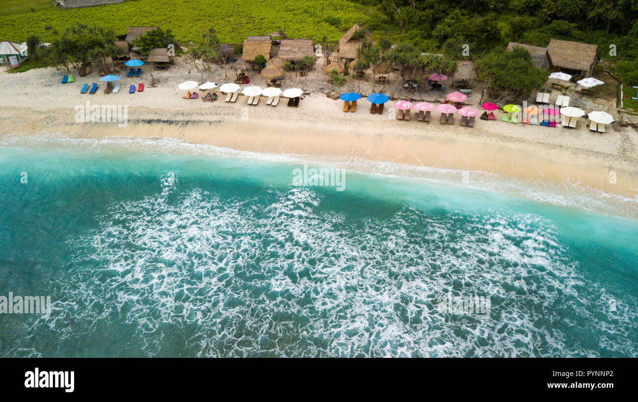 Riprese aeree del Atuh baia di spiaggia con ombrellone e barre di legno in Nusa Penida island, Bali, Indonesia Foto Stock