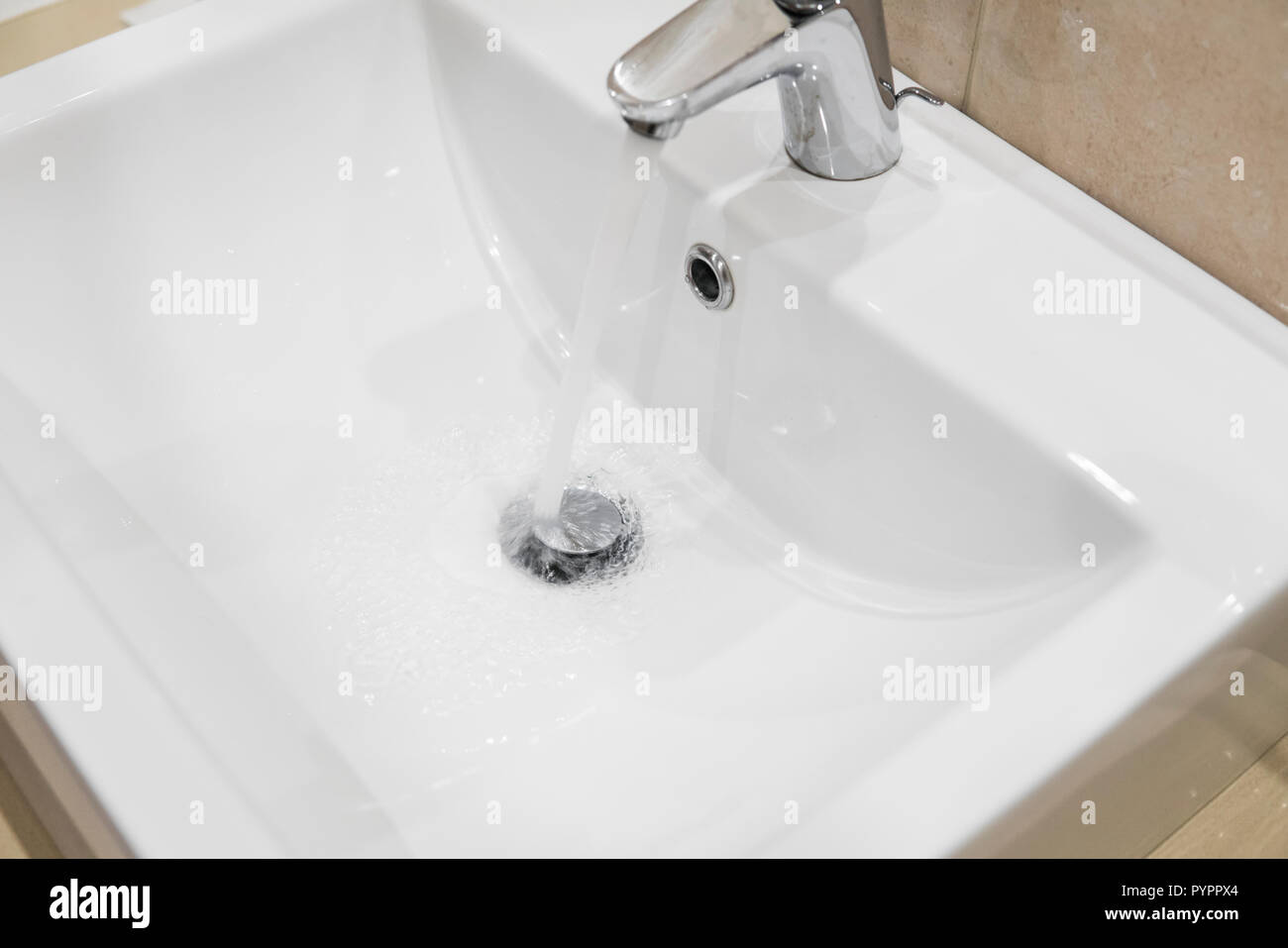 Il lavandino del bagno rubinetto con acqua corrente. Leva singola cromo monoblocco rubinetto miscelatore sul lavandino del bagno. Foto Stock