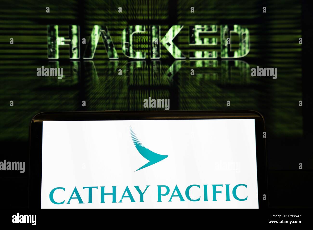 Cathay Pacific Logo visualizzato su uno smartphone di fronte a uno sfondo che legge hacked. La compagnia aerea con sede a Hong Kong Cathay Pacific ha riferito che vi è stata una grave perdita di dati è accaduto nel marzo 2018 con dati di circa 9,4 milioni di passeggeri è stata compromessa durante la violazione, con 860.000 i numeri di passaporto, 245.000 Hong Kong numeri della carta d'identità, 403 scaduto i numeri di carta di credito e 27 numeri di carta di credito senza il codice CVV essendo accessibile. Foto Stock